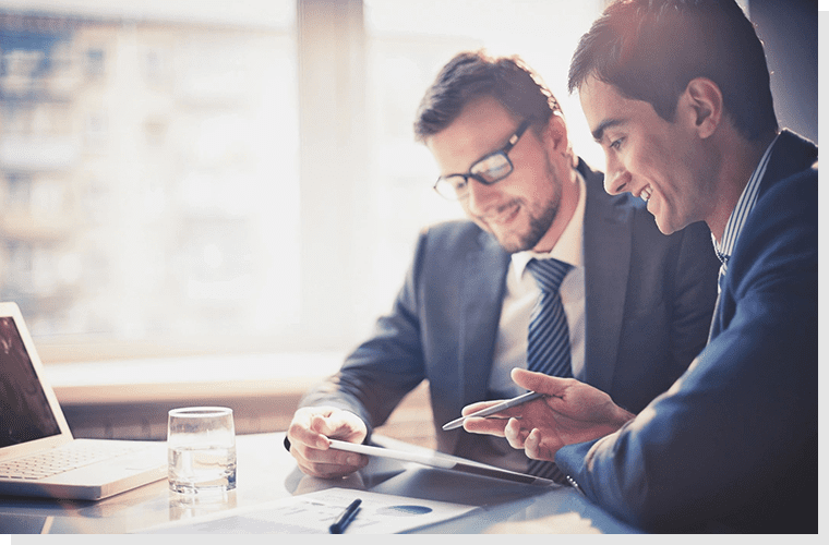 Two men in suits looking at a tablet.