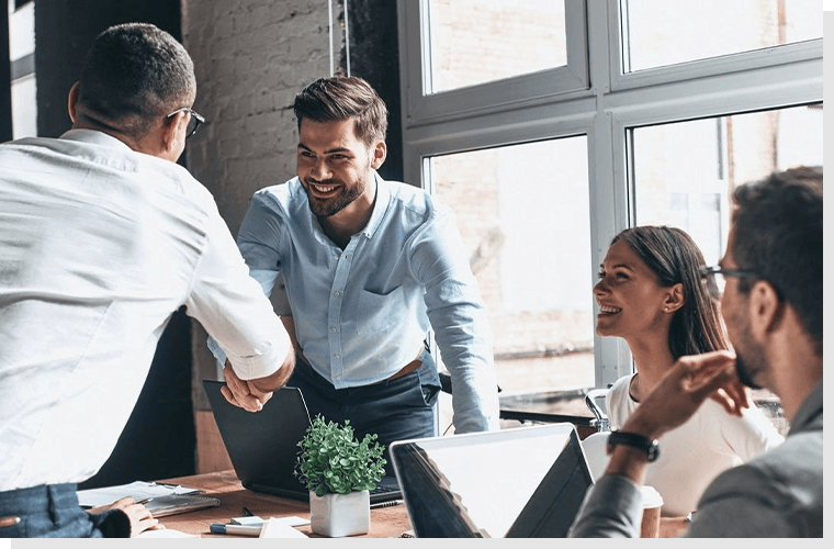 A group of people sitting around a table shaking hands.